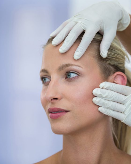 Doctor examining female patients face from cosmetic treatment